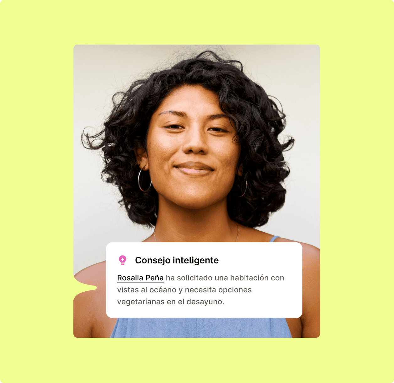 Mujer de pelo oscuro rizado sonriendo, con pendientes de aro y un top azul.