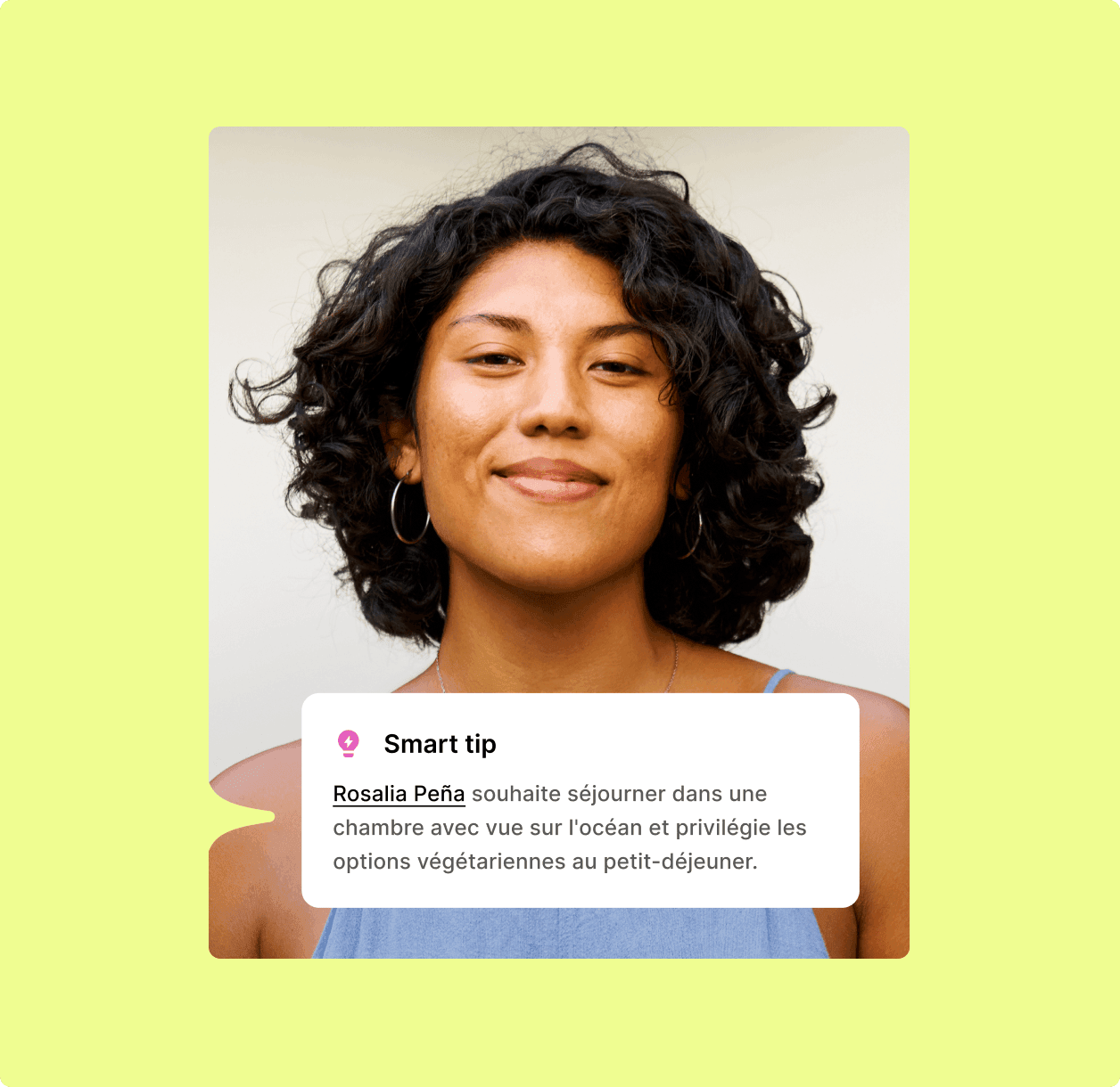 Femme souriante aux cheveux noirs bouclés, portant des boucles d'oreilles et un haut bleu.