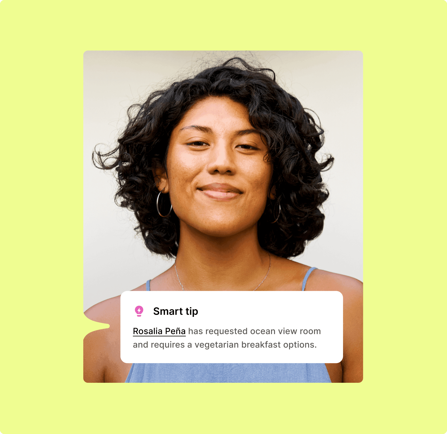 Woman with curly dark hair smiling, wearing hoop earrings and a blue top.