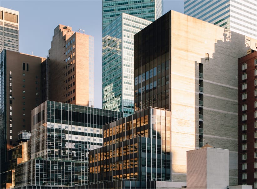 Modern skyscrapers with glass and concrete facades in a dense cityscape during daytime.