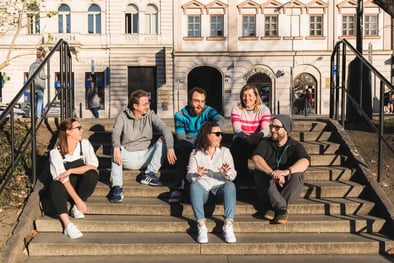 Group of Mews employees smiling and sitting together on some steps
